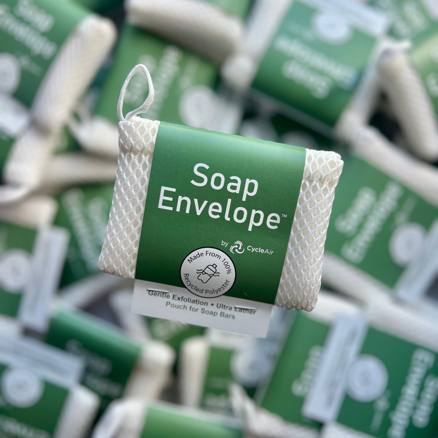 White soap envelope with green packaging above other soap envelopes on a desk.